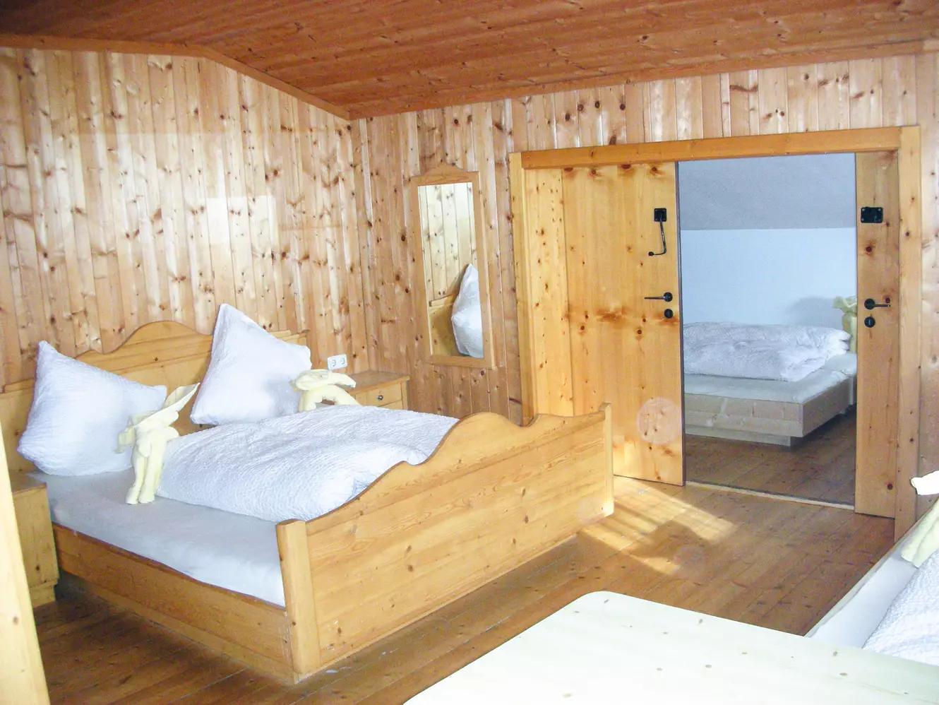 Raum mit Doppelbett und Schiebetür zu weiteren Betten