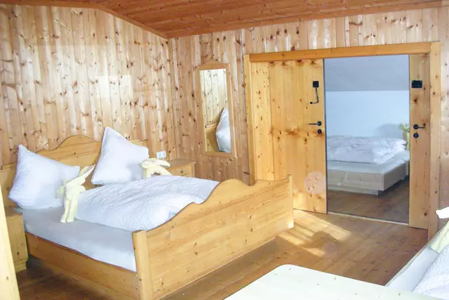 Raum mit Doppelbett und Schiebetür zu weiteren Betten