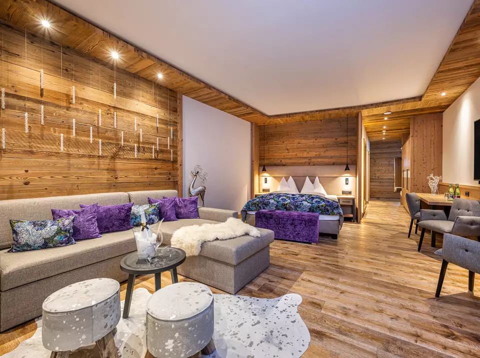 Couch mit bunten Kissen, Tisch und Doppelbett im Hintergrund