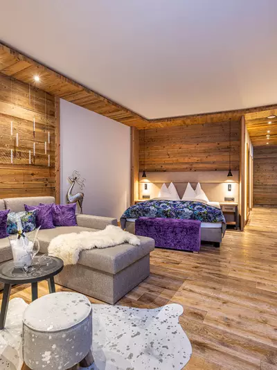 Couch mit bunten Kissen, Tisch und Doppelbett im Hintergrund