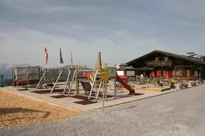 Ansicht Spielplatz und dahinter Terrasse mit Sitzgelegenheiten