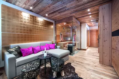 Couch mit pinken Kissen, im Hintergrund die Sauna mit Infrarotkabine