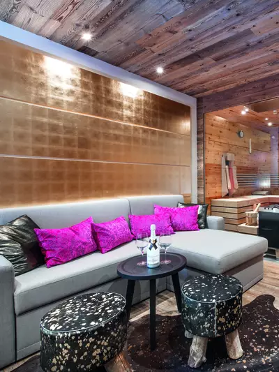 Couch with pink cushions, sauna with infrared cabin in the background