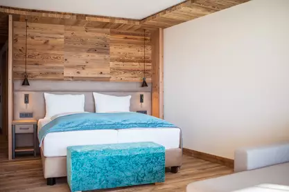 Doppelbett mit blauer Tagesdecke und Sitzbank