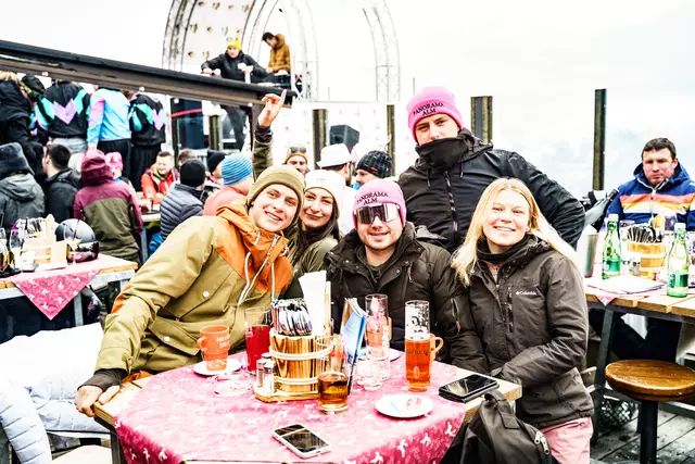 Gut gelaunte Partygäste, im Hintergrund der DJ der auflegt